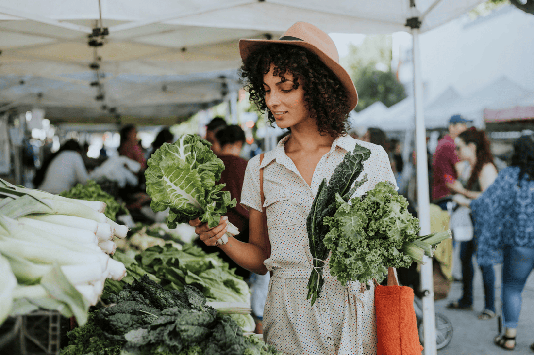 woman buying a leafy green vegetable while at a farmers market