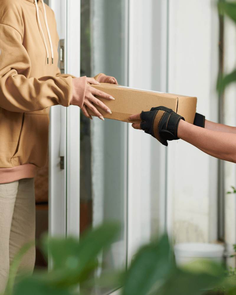 woman receiving her auto-delivery from a mail carrier at her front door.