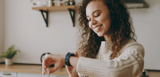 Woman in a kitchen wearing a white sweater checking her watch for best time to take collagen