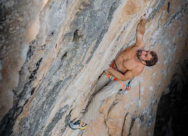 climber, Chris Sharma rock climbing on a steep wall.